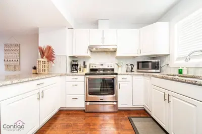 a kitchen with white cabinets and a stainless steel oven at Cozy 3BD w/AC, Patio, Theatre Room, 15 min to DT in Edmonton