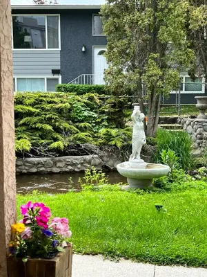 a statue of a woman sitting on a fountain in a garden at Kelowna little Island near Downtown, lake, hospital and Okanagan Collage in Kelowna