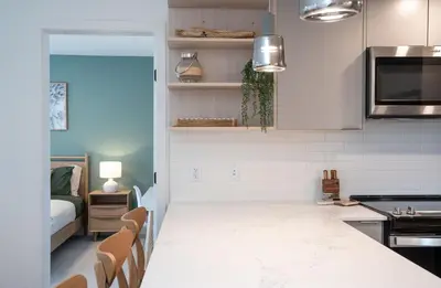 a kitchen with white cabinets and a living room at Stoked On Revy - Family Condo in Revelstoke in Revelstoke