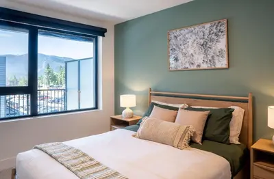 a bedroom with a bed and a large window at Stoked On Revy - Family Condo in Revelstoke in Revelstoke