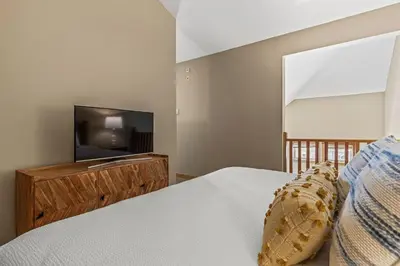 a bedroom with a bed and a flat screen tv at Top Floor Wolf - Best Views With Pool and Hot tub in Canmore
