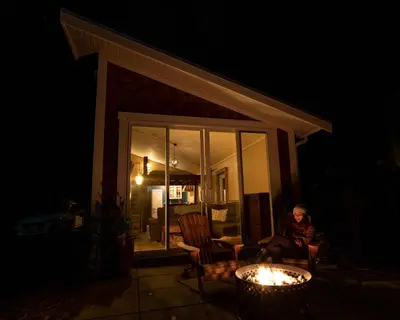 a woman sitting in a chair on a patio at night at Tiny house & Sauna on Lakefront Farm Oasis in Merville