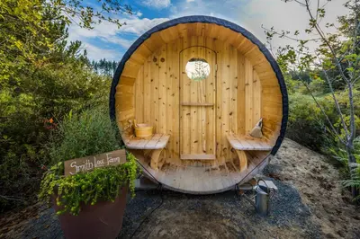 a wooden cabin with two benches in front of a door at Tiny house & Sauna on Lakefront Farm Oasis in Merville