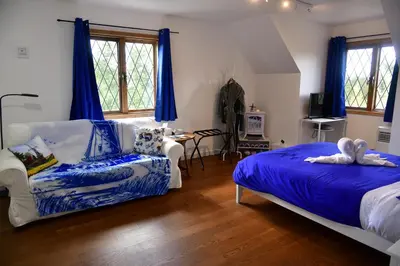 a bedroom with blue curtains and a bed and a chair at The Blue Cottage B&B in Seventy Mile