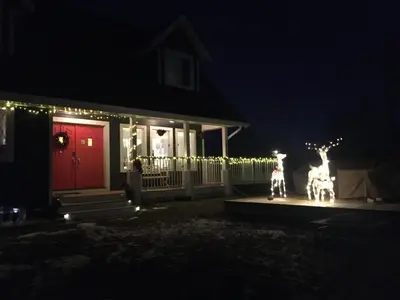 a house with christmas lights in front of a red door at The Blue Cottage B&B in Seventy Mile