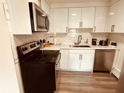a kitchen with white cabinets and a black dishwasher at unit #203 Cozy Mountain View 1BR in DT in Canmore