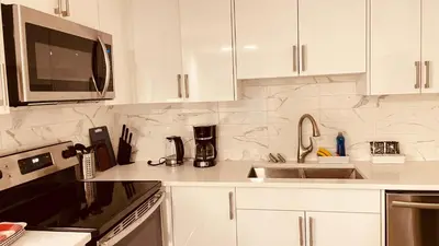 a kitchen with white cabinets and a sink and a microwave at unit #203 Cozy Mountain View 1BR in DT in Canmore