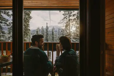 a man and a woman sitting on a porch looking out a window at Post Hotel & Spa in Lake Louise