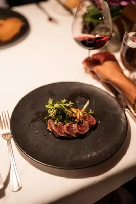 a steak on a black plate on a table with a glass of wine at Post Hotel & Spa in Lake Louise