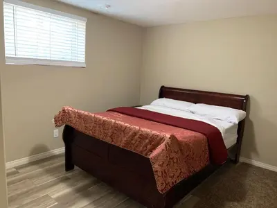 a bedroom with a bed with a red blanket and a window at Divine Homes in Calgary