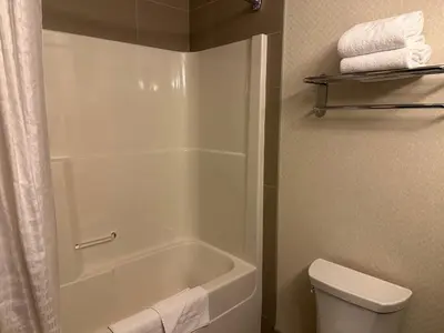 a bathroom with a shower and a toilet and towels at Kanata Whitecourt in Whitecourt