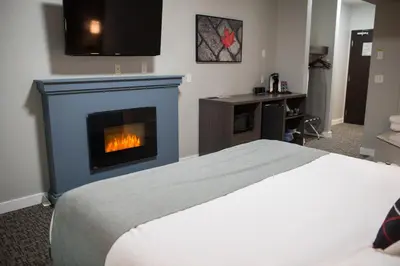 a bedroom with a bed and a fireplace at Kanata Whitecourt in Whitecourt
