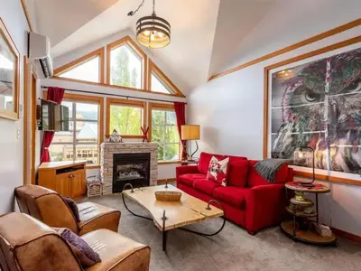 a living room with a red couch and a fireplace at Glacier Lodge Steps to Trails and Nature in Whistler