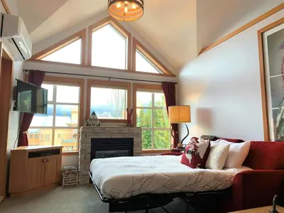 a living room with a bed and a fireplace at Glacier Lodge Steps to Trails and Nature in Whistler