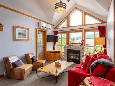 a living room with a red couch and a fireplace at Glacier Lodge Steps to Trails and Nature in Whistler
