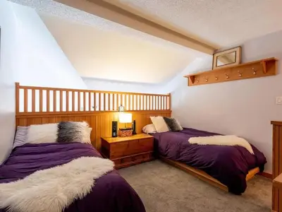 two beds in a room with purple and white sheets at Glacier Lodge Steps to Trails and Nature in Whistler