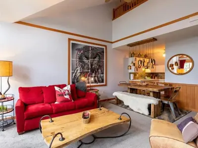 a living room with a red couch and a wooden table at Glacier Lodge Steps to Trails and Nature in Whistler