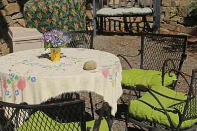 a table with chairs and a vase of flowers on it at Thistle Dew Cottage in Ganges