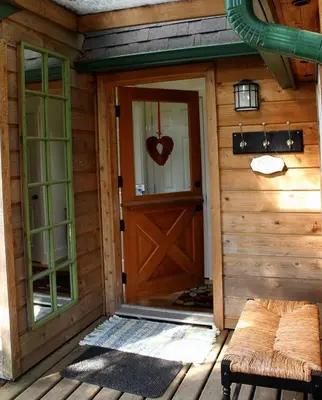an entrance to a cabin with a door and a bench at Thistle Dew Cottage in Ganges