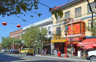 a busy city street with buildings and cars on the road at Be Close To Chinatown When You Are In The Ironwork Building in Victoria