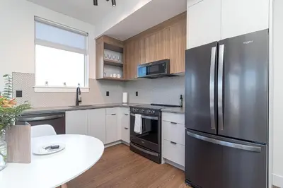 a kitchen with a stainless steel refrigerator and a table at Be Close To Chinatown When You Are In The Ironwork Building in Victoria