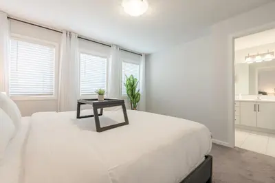 a white bedroom with a bed with a table on it at 3bedroom Stylish Getaway by the Park with 2-Car Garage in Calgary