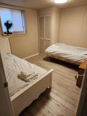 a bedroom with two beds and a window and a window at Economical Homestay hostel in Burnaby