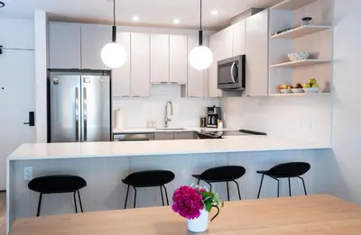 a kitchen with white cabinets and black bar stools at Cabot Views by Revelstoke Vacations in Revelstoke