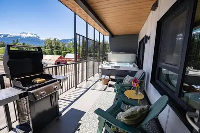 a screened in porch with a grill and a table and chairs at Cabot Views by Revelstoke Vacations in Revelstoke