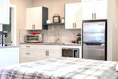 a kitchen with white cabinets and a stainless steel refrigerator at RainCoast Retreat at Shawnigan Lake! in Shawnigan Lake
