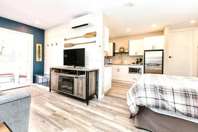 a bedroom with a bed and a tv and a kitchen at RainCoast Retreat at Shawnigan Lake! in Shawnigan Lake
