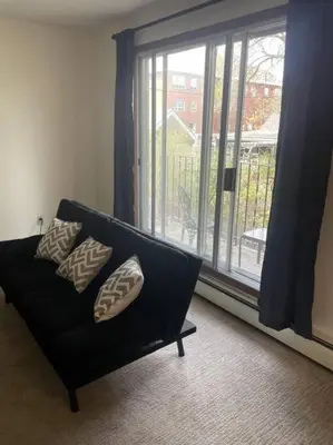 a black couch in a living room with a window at Stunning 1 Bedroom Apartment in Camrose