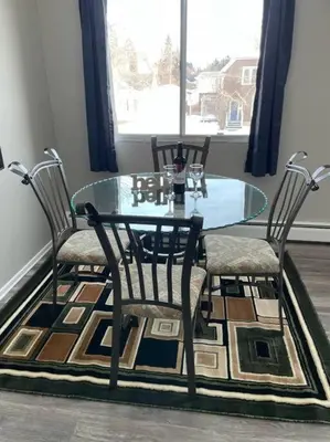 a glass table with two chairs and a table and a window at Exquisite 2 Bedroom Apartment in Camrose