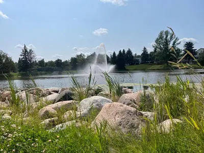 a bunch of rocks in front of a lake with a fountain at Exquisite 2 Bedroom Apartment in Camrose
