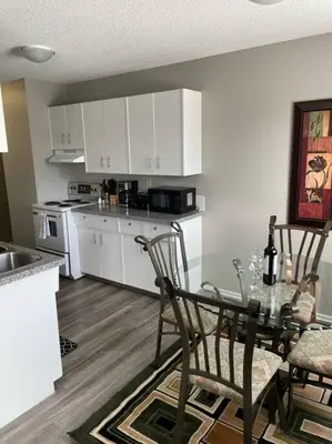 a kitchen with a glass table and chairs in a room at Exquisite 2 Bedroom Apartment in Camrose