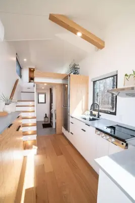 a modern kitchen with white cabinets and a staircase at Refuge Bay's Aqua Tiny Home - Luxury Off Grid Escape in Cherhill