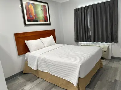 a bedroom with a large bed with white sheets at RAMSHORN MOTEL in Lumby