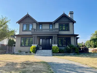 a large house with a porch and a driveway at Vancouver Airport guesthouse in Vancouver