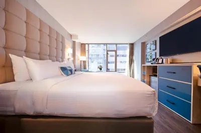 a bedroom with a large white bed and a large window at Hotel BLU in Vancouver