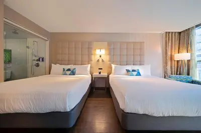 two beds in a hotel room with white sheets and blue pillows at Hotel BLU in Vancouver