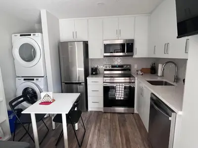 a kitchen with white cabinets and stainless steel appliances at Mountain View Studio in Town in Canmore
