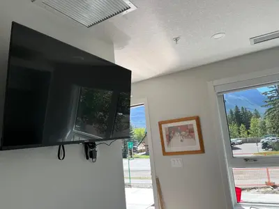a flat screen tv hanging on a wall next to a window at Mountain View Studio in Town in Canmore