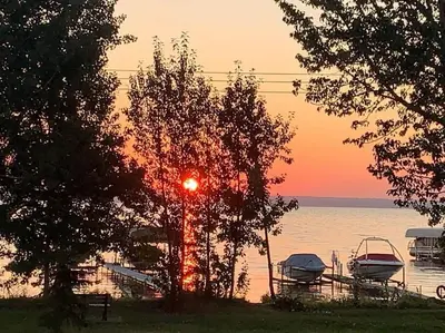 a sunset over a lake with boats in the water at 4 Seasons Lakeview Cottage w/ Private Boating Dock in Westerose