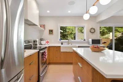 a kitchen with wooden cabinets and a stainless steel refrigerator at The Bayside Cottage by EMR Vacation Rentals in North Saanich