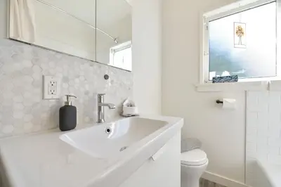 a white bathroom with a sink and a toilet at The Bayside Cottage by EMR Vacation Rentals in North Saanich