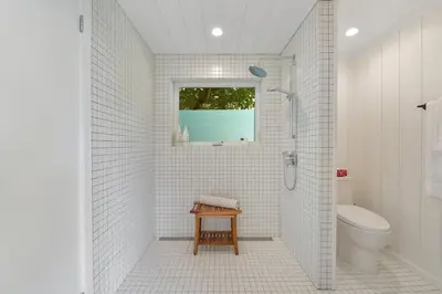 a white bathroom with a shower and a toilet at The Bayside Cottage by EMR Vacation Rentals in North Saanich