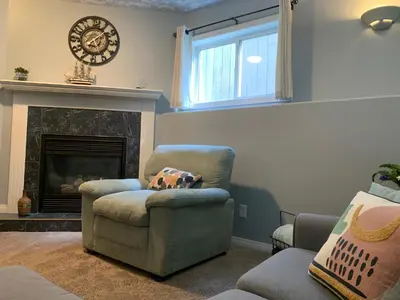 a living room with a chair and a fireplace at Cozy Basement Suite close to Downtown,Edmonton in Edmonton