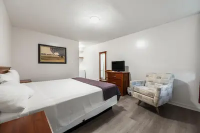 a bedroom with a bed and a chair and a television at Grantview Inn in Surrey