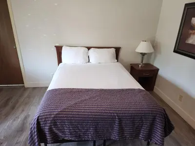a bedroom with a bed with a purple blanket on it at Grantview Inn in Surrey