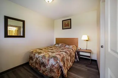 a hotel room with a bed and a mirror at Canadas Best Value Inn Fort St John in Fort Saint John